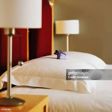 A hotel-room safe and a wrapped chocolate placed on a pillow, illustrating two guest amenities.