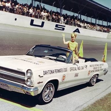 A pace car leading a group of race cars around a track.