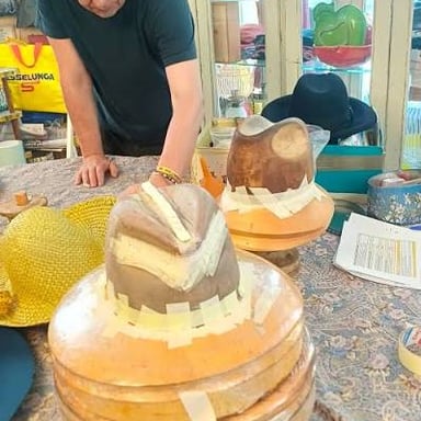 A milliner working on hats in a workshop.
