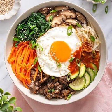 A bowl of bibimbap with rice beneath its toppings.