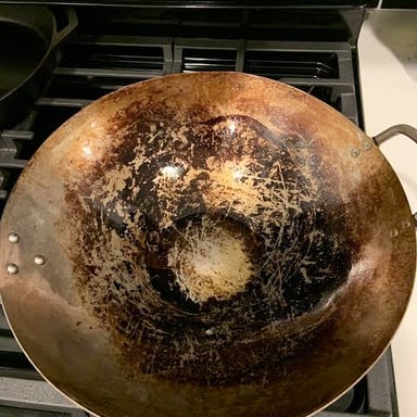A well-used wok with a dark seasoned patina on its cooking surface.