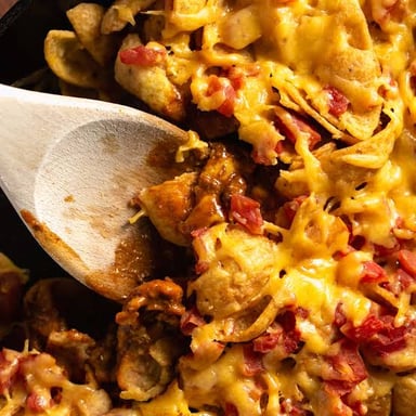 A serving of Frito pie, with corn chips covered in chili and toppings.