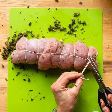 A bird prepared for roasting with its legs tied together using kitchen twine.