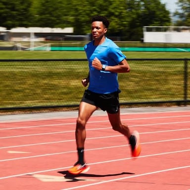 A runner moving faster on a track, illustrating picking up the pace.