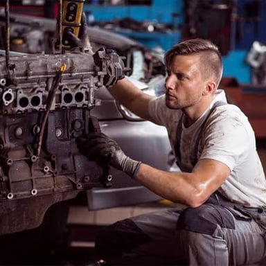 A mechanic examining a car engine closely.