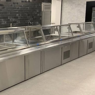 A cafeteria serving line with trays ready for diners.