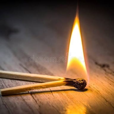 A lit wooden match beside a few unlit matches