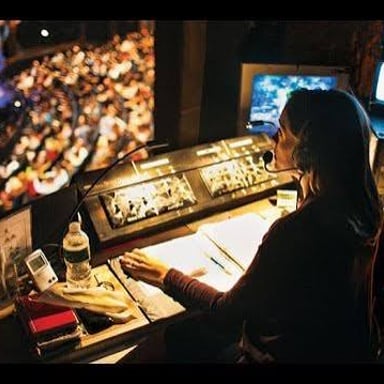 A stage manager signals to an actor waiting to enter from the wings.