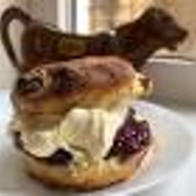 A baked scone served with jam and clotted cream.