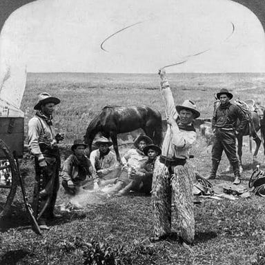 A cowhand swings a looped rope while working with livestock.