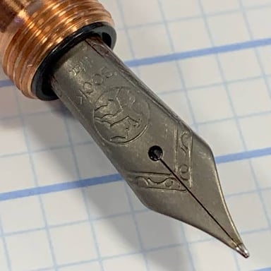 Close-up view of the pointed metal tip of a quill pen