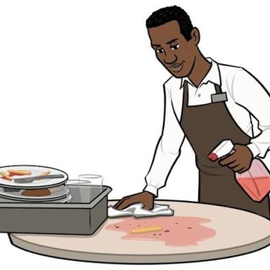 A restaurant worker clearing used plates from a table.