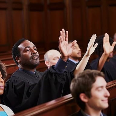 A juror raises a hand while taking an oath in court.