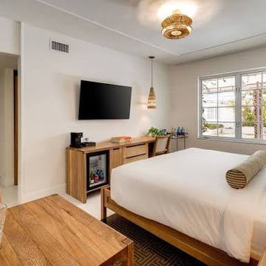 A hotel guest room with a bed and a window.