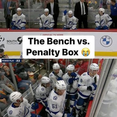A hockey player sits in the penalty box during a game.