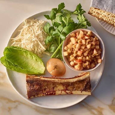 A Passover seder plate displaying traditional symbolic foods, including a bitter herb.