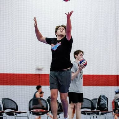 A volleyball player serves the ball over the net.