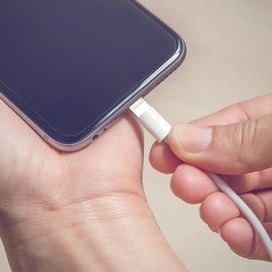 A smartphone connected to a charging cable.