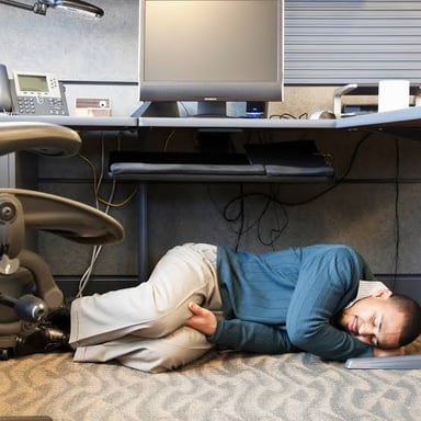 A person lounging at a desk while work remains unfinished.