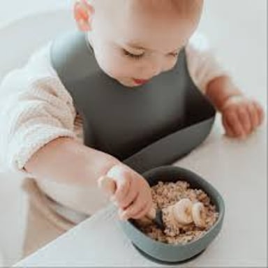 An infant wearing a bib over the chest while eating.