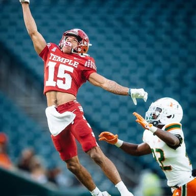 A wide receiver reaching to catch a football.