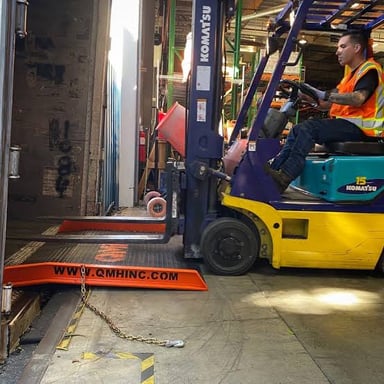 A forklift raises a pallet inside a warehouse.