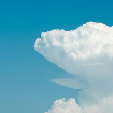 White, puffy cumulus clouds against a blue sky.