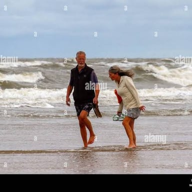 A person walking through shallow water at the beach.