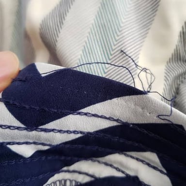 Loose threads coming away from a fabric seam.