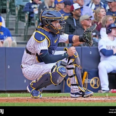 A baseball catcher crouches behind home plate.