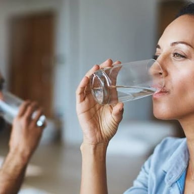 A person drinking from a glass of water.