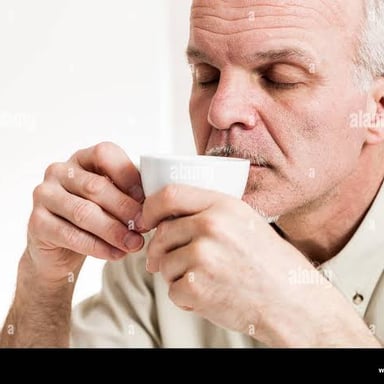 A person taking a small sip of tea from a cup.