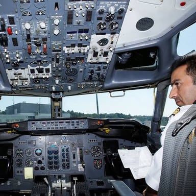 A commercial pilot seated at the controls in an airplane cockpit.
