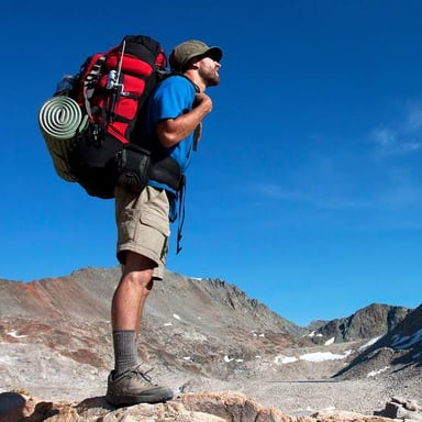 A hiker is being provided with a backpack and outdoor gear.