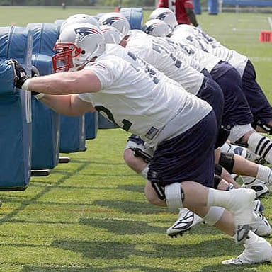 American football offensive linemen blocking during a play