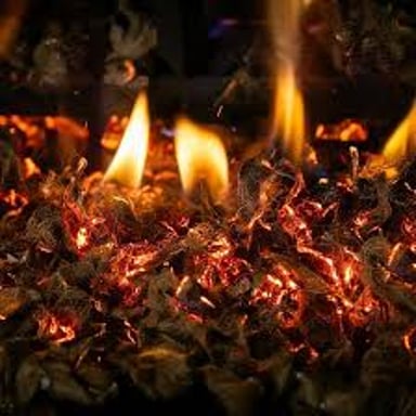 Small glowing cinders remaining in a fireplace after a fire.