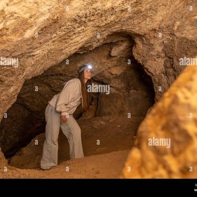 A cave explorer wearing a headlamp inside a cave.