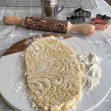 A rolling pin dusted with flour beside prepared dough.