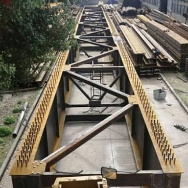 Heavy steel girders supporting a bridge under construction.