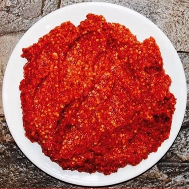 Red harissa chili paste served in a small bowl.