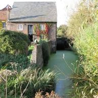 A water channel carrying a stream beside a historic mill.