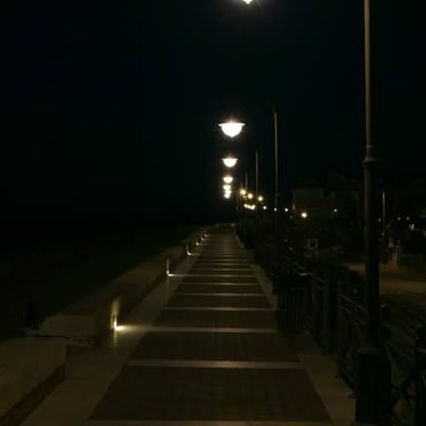 A streetlight casts light over a sidewalk at night.