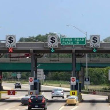 Cars passing through tollbooths on a highway.