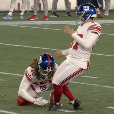 A football player kicking a stationary ball toward the goalposts.