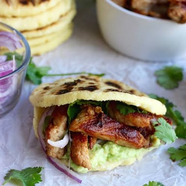 A round cornmeal arepa split open and filled with savory ingredients.
