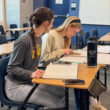 A student writing calculus equations in a notebook.