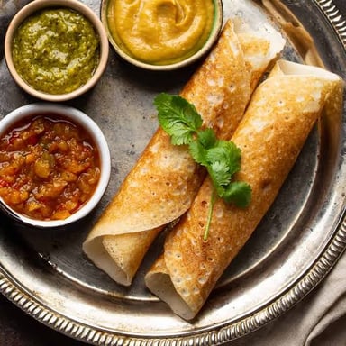 A crisp dosa served on a plate with chutney.