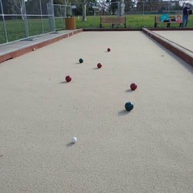 Bocce balls resting on an even playing surface beside the smaller target ball.
