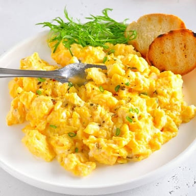 A hotel breakfast buffet tray filled with scrambled eggs