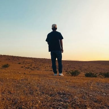 A solitary person standing by themself in a wide landscape